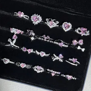 Colección de elegantes anillos plateados con piedras de corazón rosa en estuche negro