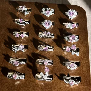 Primer plano de varios anillos de plata con piedras de corazón rosa en tabla