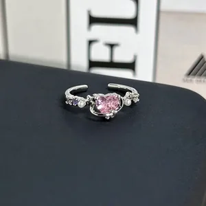 Primer plano de un elegante anillo abierto de plata con un corazón rosa y pequeñas perlas