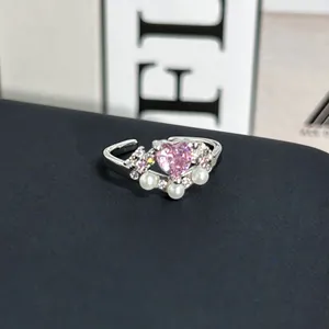 Primer plano detallado de un elegante anillo de plata con piedra de corazón rosa y perlas