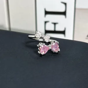 Primer plano de un anillo de lazo plateado con piedras de corazón rosa y circonio.