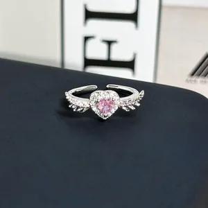 Detalle macro de un anillo romántico plateado con corazón rosa y alas laterales