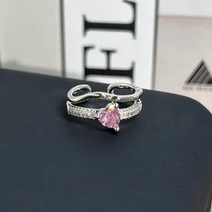 Detalle de anillo ajustable plateado con gema de corazón rosa y detalles brillantes