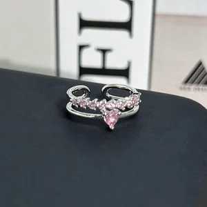 Primer plano de un anillo de plata abierto con una piedra rosa brillante en forma de corazón