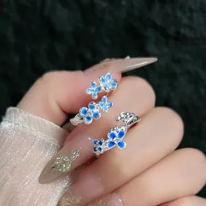 Detalle de un elegante anillo abierto de plata con flores de esmalte azul degradado