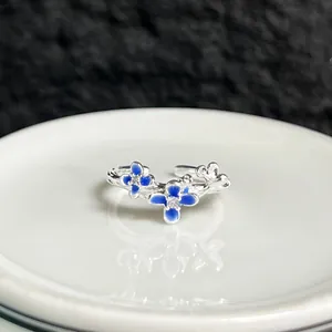 Vista detallada de un anillo abierto plateado con elegantes flores de esmalte azul