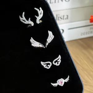 Close-up of four silver rings with antler, wing, and heart designs on black velvet