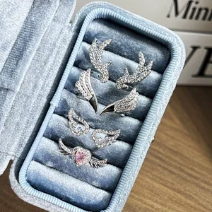 Detail view of silver antler and wing rings with pink heart gem in blue velvet box