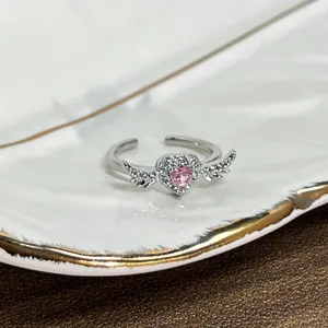 Detailed close-up of a silver angel wings ring featuring a pink heart zircon center