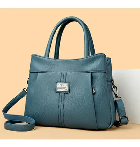 Detail view of blue textured leather handbag with elegant metal logo and broad strap