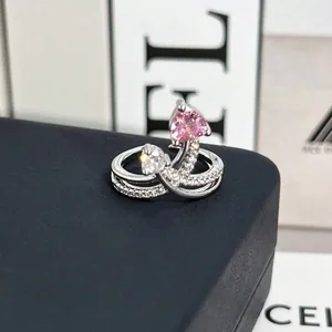 Primer plano de un elegante anillo de plata con piedras en forma de corazón rosa y blanco