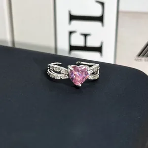 Vista macro de un anillo con gema rosa en forma de corazón y piedras laterales brillantes.