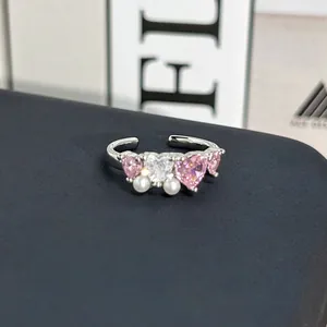 Detalle de primer plano de anillo romántico de plata con corazones rosas y perlas