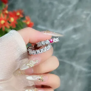 Vista macro dettagliata di un anello aperto in argento con zirconi chiari e pietra cuore rosso