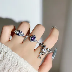 Detailed close-up showing stylish silver rings with vibrant purple crystals worn on hand.