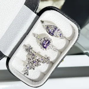 Close-up of three elegant silver rings with purple gemstones in a black jewelry box