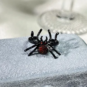 Λεπτομερής προβολή ενός μαύρου δαχτυλιδιού αράχνη με ένθετα κόκκινα κρύσταλλα πανκ