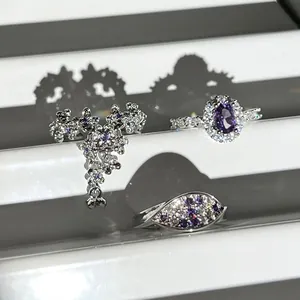 Detail view of purple crystal rings featuring floral tassel and oval pave designs