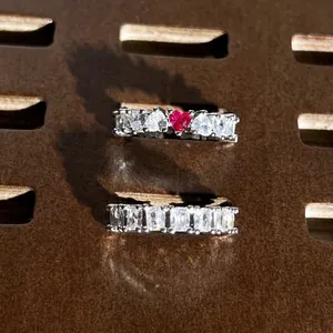 Primo piano di anelli eternity scintillanti con cuore e rettangoli su supporto marrone