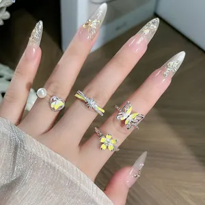 Vista detallada de anillos de plata con diseños de flores y mariposas en esmalte amarillo