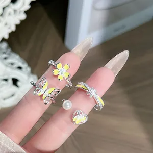 Primer plano de anillos ajustables con temática de flores amarillas y mariposas