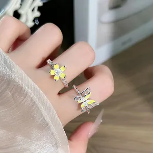 Detalle macro de elegantes anillos abiertos de plata con flores y mariposas amarillas