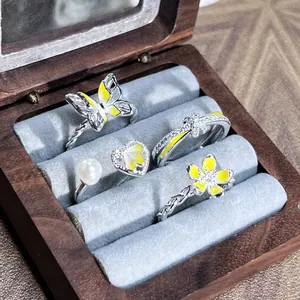 Primer plano de cuatro anillos plateados y amarillos con diseños de flores y mariposas