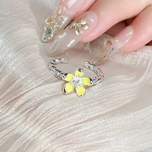 Detalle exquisito de un anillo ajustable plateado con una flor de esmalte amarillo