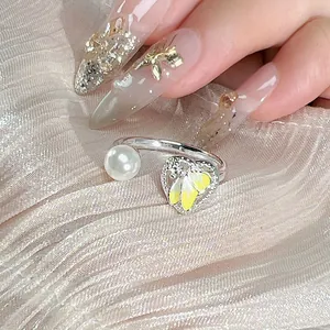 Elegante primer plano de anillo abierto con perla blanca y dije de corazón floral amarillo