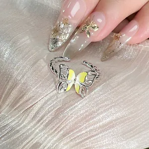 Primer plano macro de un anillo de mariposa ajustable de plata con detalles en esmalte