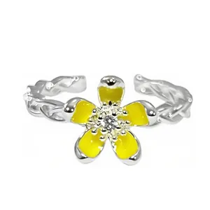 Detalle de primer plano de un anillo abierto plateado con flor de esmalte amarillo