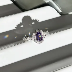 Detail view of an oval purple gemstone ring with sparkling diamond halo in silver finish.