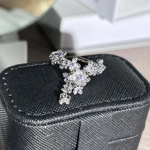 Close-up of silver-colored open ring with 3D purple floral rhinestone details