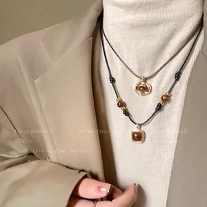 Detail shot of layered tiger's eye pendant necklace on a brown leather cord.