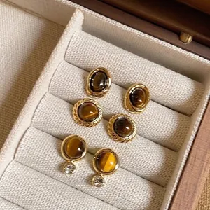 Nahaufnahme von goldenen Vintage-Ohrringen mit braunem Tigerauge-Stein in Schatulle