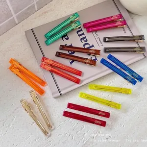 Detailed view of multiple colorful translucent acrylic duckbill hair clips on a table.