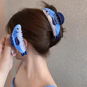 Close-up view of stylish blue fish-shaped hair shark clips worn on a model's ponytail