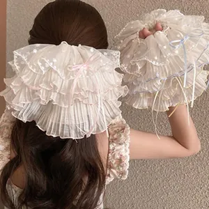 Close-up of a large ruffled cream mesh hair accessory with bow details on hair.