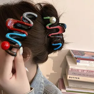 Close-up detail of wavy colorful hair claw clips with pearls in a stylish hairstyle.