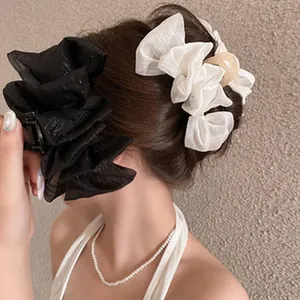 Detailed view of black and cream ruffled hair claw clips on hair