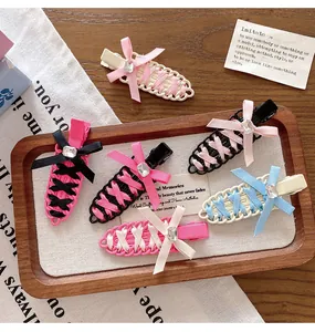 Close-up of ballet-style woven ribbon hair clips in various colors on a wooden tray