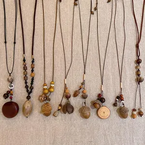 Variety of vintage ethnic beaded necklaces with wooden acorn pendants on textured cloth.