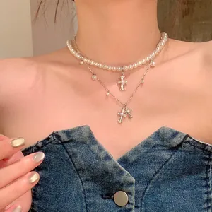 Detailed macro view of a double-layer pearl and cross pendant necklace on a model's neck