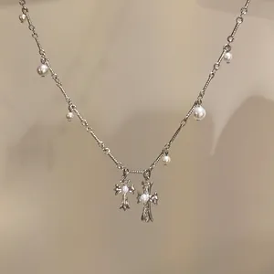 Detailed macro shot of silver-tone cross pendants and small pearls on a dainty chain necklace