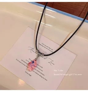 Close-up of pink flower pendant necklace with black cord on poetic background card