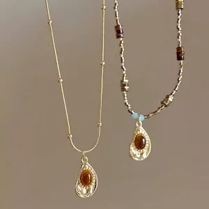 Close-up detail of vintage tiger eye stone pendants on gold chain and beaded necklaces