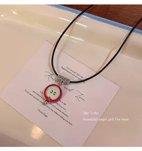 Detailed view of a unique red apple pendant necklace with black cord on a white card.