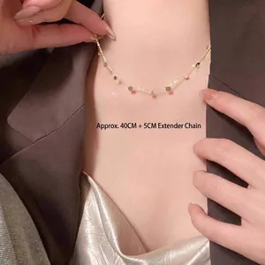 Close-up detail of a gold chain necklace with round pendants on a model wearing brown.