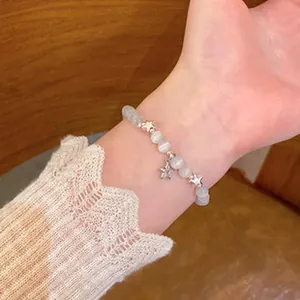 Detailed close-up showing a retro beaded bracelet with silver star charms on a woman's wrist