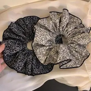 Detail view of two vintage-style floral scrunchies in black and cream fabrics.